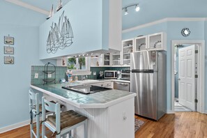 A kitchen with a central island, white cabinetry, a stainless steel refrigerator, and a microwave. - 🏖️Walk to Beach | Great Location | Lule Cottage🏖️ (Destin)