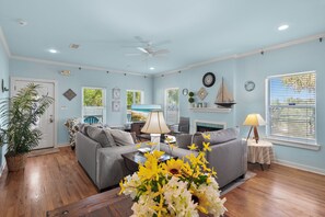 A living room with a gray sofa, a coffee table, a lamp, and a fireplace. - 🏖️Walk to Beach | Great Location | Lule Cottage🏖️ (Destin)