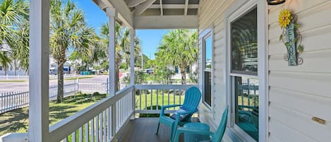 A porch with two chairs, a welcome sign, and a lantern.