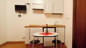 A compact kitchen with a small table and two chairs, a sink, and a cabinet above.
