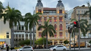 A historic building with a central dome and two smaller domes, surrounded by palm trees and modern cars. - Charming 1-bedroom loft in downtown Rio de Janeiro. (Rio de Janeiro)
