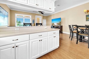 A kitchen with white cabinets, a dining area with a table and chairs, and a ceiling fan. - 🦀Walk to Beach | Pet Friendly | Community Pool | Casa Valencia🦀 (Panama City Beach)