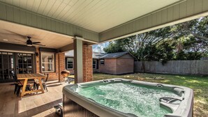 Ein Garten mit Whirlpool, Holztisch und Stühlen.