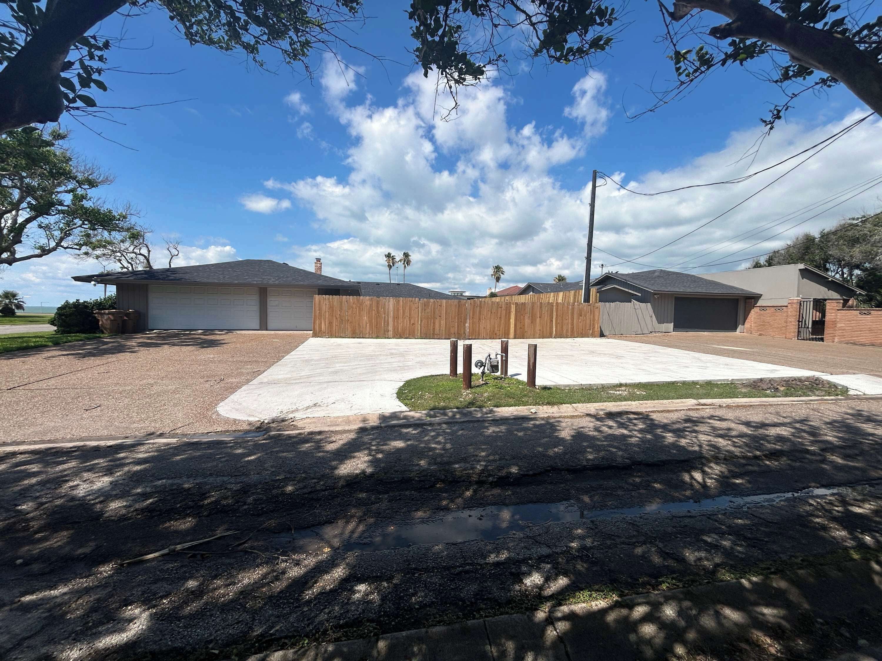 Una propiedad residencial con garaje, valla de madera y camino de entrada pavimentado.