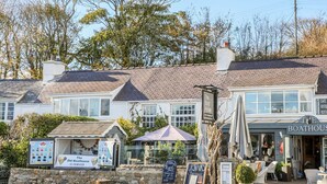 A traditional building with a sign for 'The Boat House' cafe and restaurant, stone walls, and outdoor seating. - Red Wharf Retreat (Pentraeth)