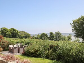A garden with outdoor furniture, a pond, and trees. - Red Wharf Retreat (Pentraeth)
