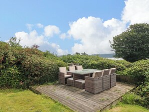 A patio with wicker furniture and a view of the sea. - Red Wharf Retreat (Pentraeth)