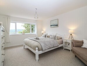 A bedroom with a bed, bedside tables, a nightstand, a window, and a view of the outdoors. - Red Wharf Retreat (Pentraeth)