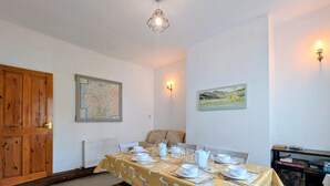Un coin repas avec une table dressée pour quatre personnes, une carte accrochée au mur et une porte.