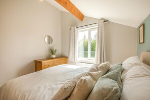 A bedroom with a bed, a wooden dresser, a window with curtains, and a mirror on the wall. - 2 Bed in Cockermouth (oc-w38209) (Cockermouth)