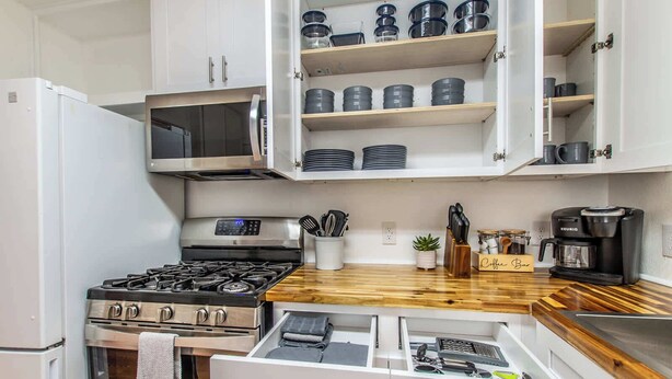 A modern kitchen with white cabinets, a stainless steel stove, and a coffee bar. - Texas Tranquility Retreat (Corpus Christi)