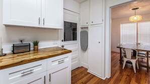 A modern kitchen with white cabinets, a wooden countertop, and a built-in oven. - Texas Tranquility Retreat (Corpus Christi)