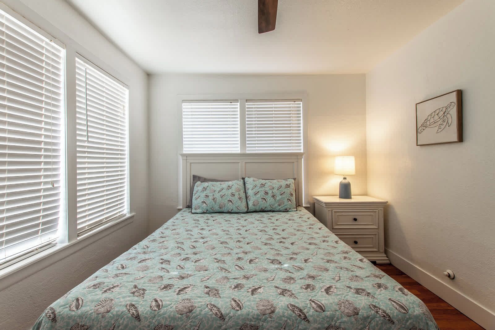 A bedroom with a bed, a nightstand, a lamp, and a framed picture on the wall.