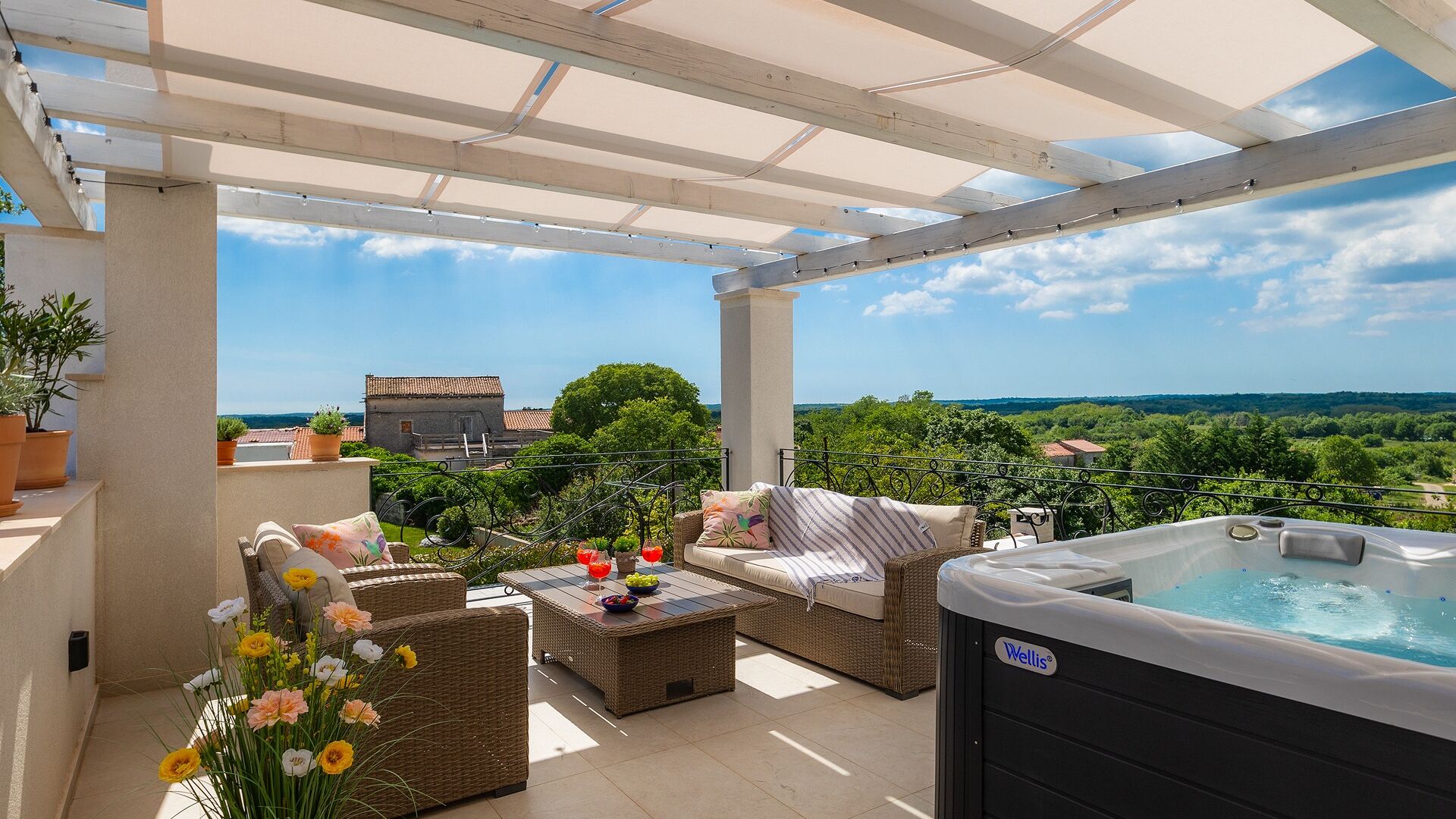Un espace extérieur abrité, aménagé avec des meubles en osier, un jacuzzi et offrant une vue sur le paysage.