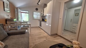 Ein kompakter Wohnbereich mit Sofa, Esstisch, Küchenzeile und Kleiderschrank.
