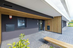 Ein modernes Gebäude mit einer Fassade aus Holzschindeln, einer Bank und einem gepflasterten Bereich.