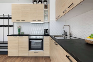 Eine moderne Küche mit Holzausstattung, einer schwarzen Arbeitsplatte, einem eingebauten Backofen und einer Edelstahl-Spüle.