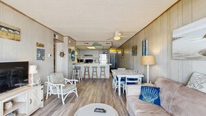 A compact living space with a TV, seating, a dining area, and a kitchenette. - Bimini 306 (Ocean City)