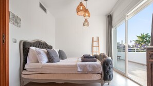 Ein Schlafzimmer mit einem Bett, einer Holzleiter und Blick ins Freie.