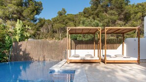 Ein Pool mit einer Holzpergola und einer weißen Wand im Hintergrund.