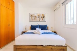 Ein Schlafzimmer mit Bett, Nachttisch, Fenster und Kleiderschrank.