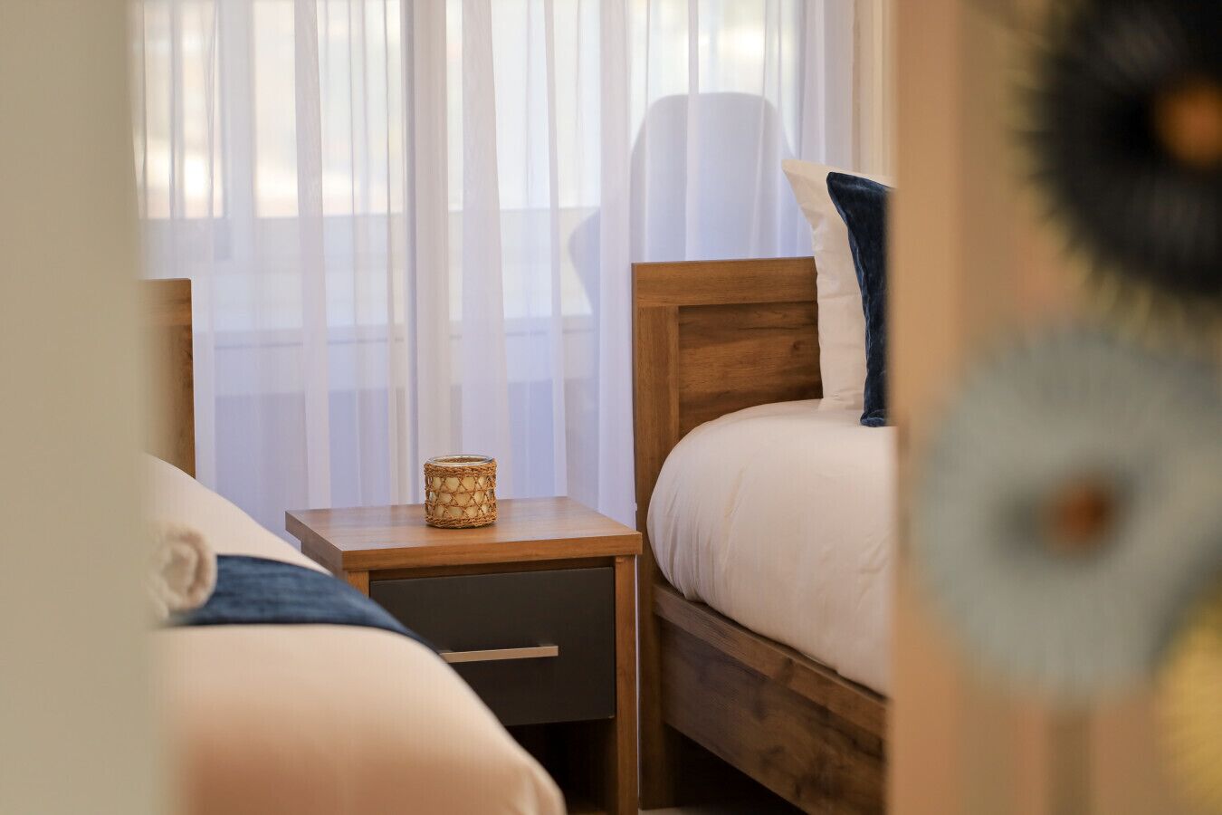 A bedroom with a wooden headboard, a bedside table with a lamp, and a small decorative item.