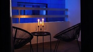 A modern interior with a table and chairs, a window with a blue tint, and a candlelit ambiance. - TelMar Central Modern Retreat (Larnaka)