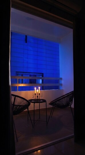 A modern interior with a table and chairs, a window with a blue tint, and a candlelit ambiance. - TelMar Central Modern Retreat (Larnaka)