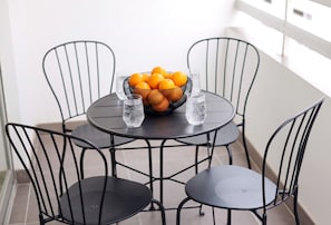 A round table with a fruit bowl and glasses, surrounded by four chairs. - TelMar Central Modern Retreat (Larnaka)