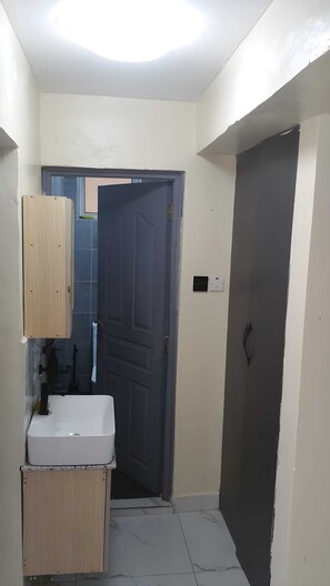 Ein Badezimmer mit Waschbecken, Holzkabinetten und einer dunklen Tür.