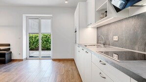 A modern kitchen with white cabinets, a grey countertop, and a built-in TV. - Accessible Apartment '3' with Garden, Wi-Fi and Air Conditioning (Auer)