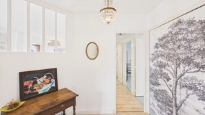 Ein Flur mit einer hölzernen Bank, einem gerahmten Gemälde, einer Chandelieber und einem großflächigen Wandbild.