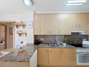 Eine Küche mit Holzausstattung, Granit Arbeitsplatten, einem eingebauten Ofen und einer Kaffeemaschine.