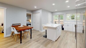 Una cocina moderna con una mesa de comedor de madera, sillas blancas y una isla blanca.