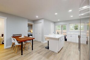 Una cocina moderna con una mesa de comedor de madera, sillas blancas y una isla blanca.
