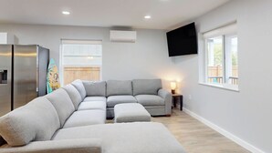 Una sala de estar moderna con un sofá seccional, un televisor de pantalla plana y una ventana con vistas.
