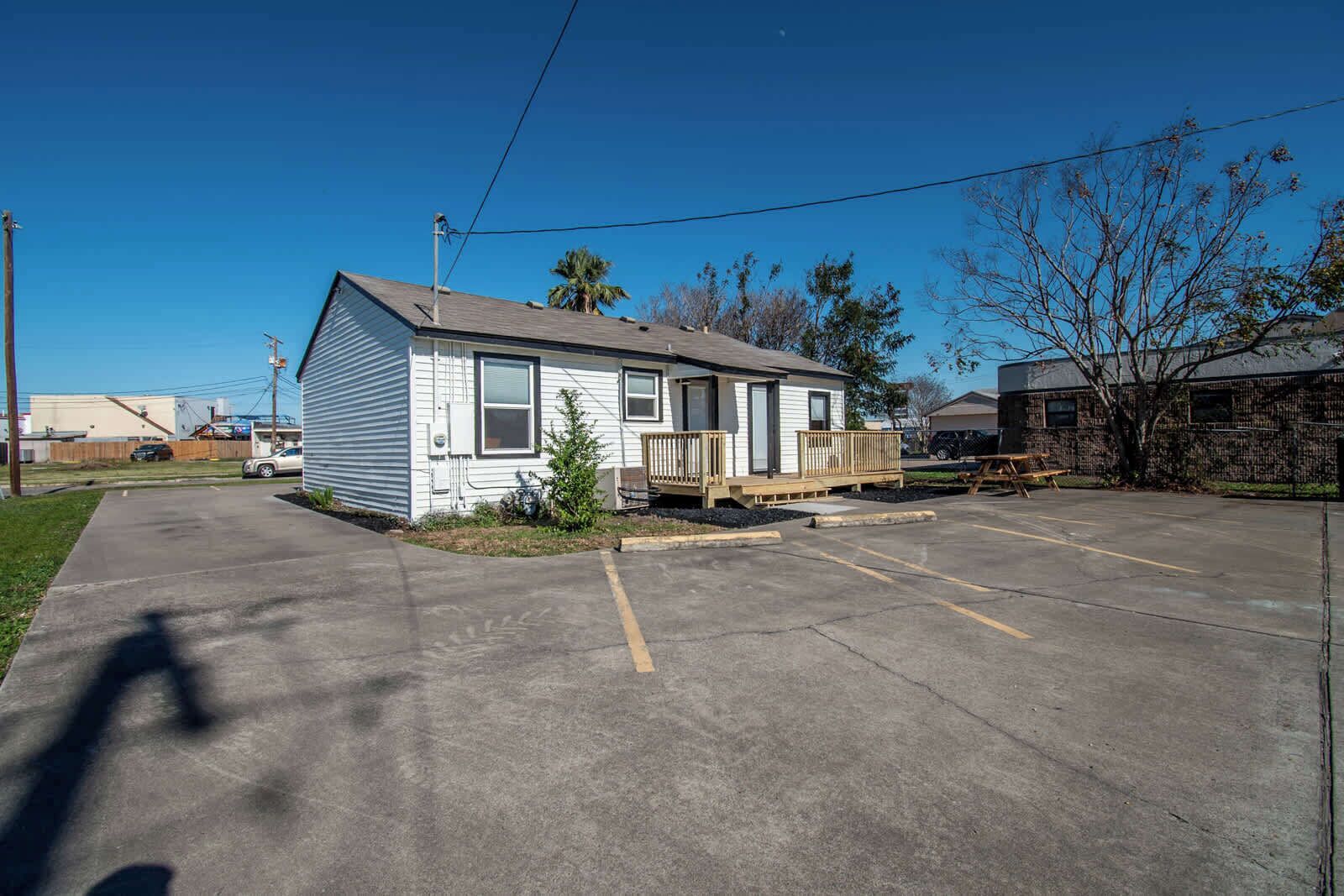 A single-story house with a front porch, a small yard, and a parking lot.