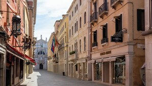 A street with historic buildings, a clear sky, and a distant cathedral. - Dalèt (Venice)