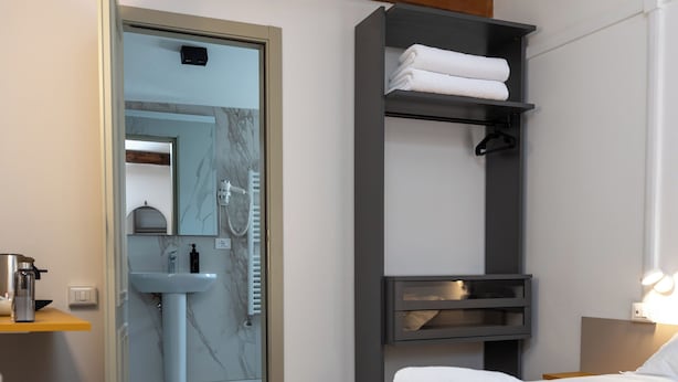 A modern hotel room with a bed, a bathroom, a suitcase, and a wooden ceiling beam. - Dalèt (Venice)