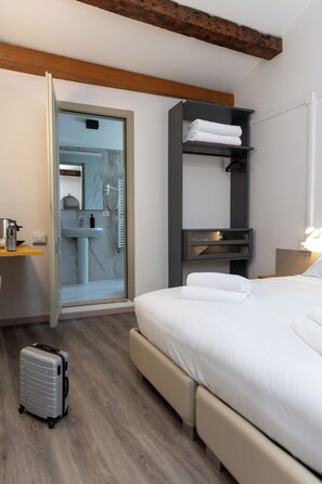 A modern hotel room with a bed, a bathroom, a suitcase, and a wooden ceiling beam. - Dalèt AI experience - NO RECEPTION - 400m from San Marco - Adults Only (Venice)
