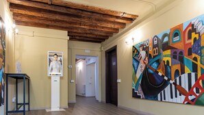 A hallway with wooden beams, a painting, and a framed photograph on the walls. - Dalèt (Venice)