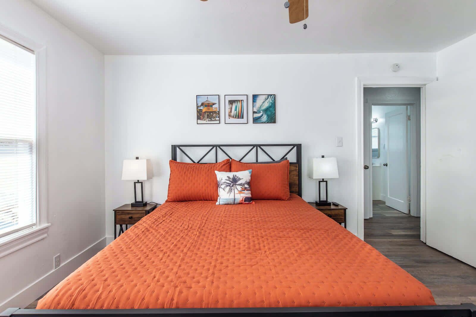 Ein Schlafzimmer mit einem großen Bett, zwei Nachttischen, einem Kopfteil und drei gerahmten Bildern an der Wand.