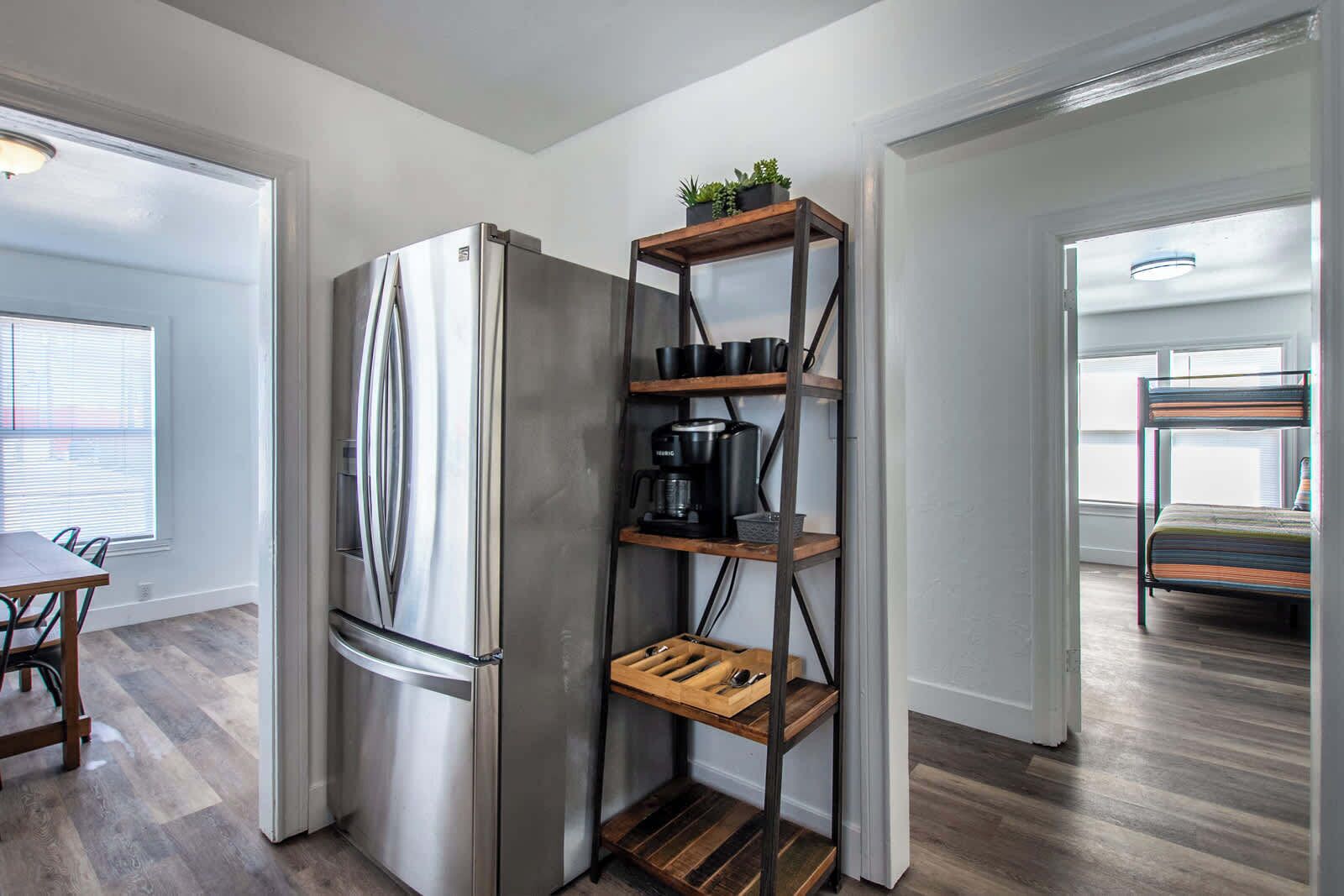 Una cocina moderna con un refrigerador de acero inoxidable, estantes de madera y una cafetera.