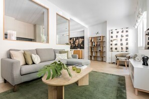 Ein modernes Wohnzimmer mit einem grauen Sofa, einem Holztisch und einem grünen Teppich.