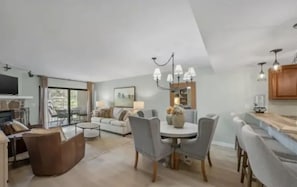 A spacious living area with a dining table, chairs, a sofa, and a fireplace.