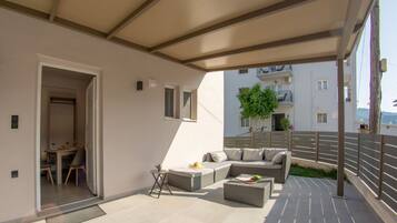 Ein Balkon mit einer Couch, einem kleinen Tisch und einem Blumentopf.