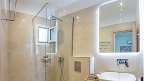 A modern bathroom with a glass-enclosed shower, a white sink, and a large mirror.