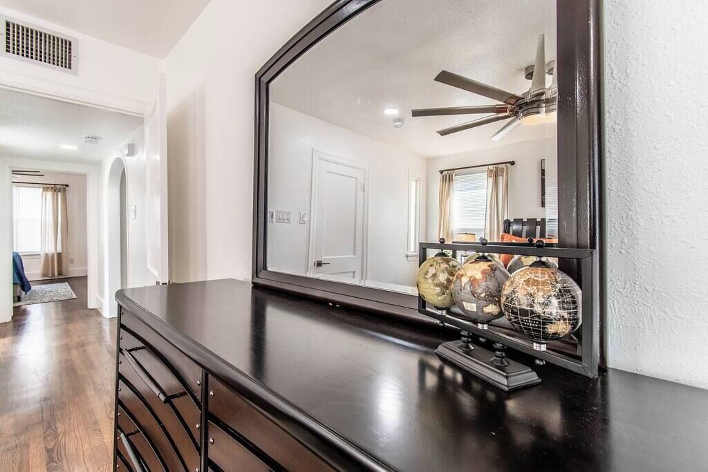 A room with a dark wooden dresser, a large mirror, and a ceiling fan.
