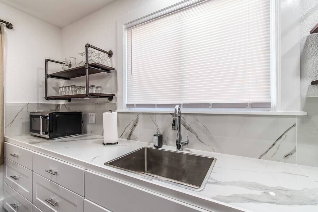 A modern kitchen with a stainless steel sink, a microwave, and a wine rack.