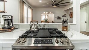 A modern kitchen with a stainless steel stove, a coffee maker, and a kettle on the counter. - Tranquil Terrace - Duplex #1 (Corpus Christi)